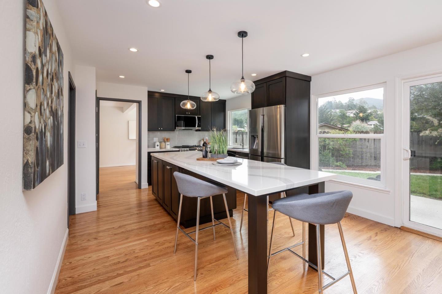 3 Yellowstone Way Pacifica, CA 94044 - Photo 7 of 18 a kitchen with stainless steel appliances kitchen island granite countertop a table chairs refrigerator and sink