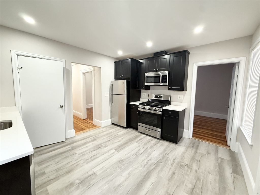 a kitchen with granite countertop a refrigerator and a stove top oven