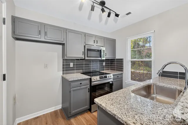 a kitchen with granite countertop a sink stainless steel appliances and cabinets