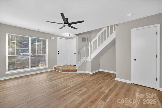 a view of empty room with wooden floor and fan