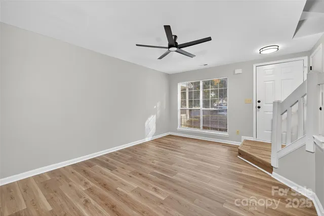 a view of empty room with wooden floor and fan