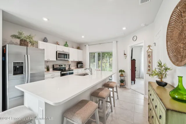 a kitchen with stainless steel appliances a white table chairs and a refrigerator