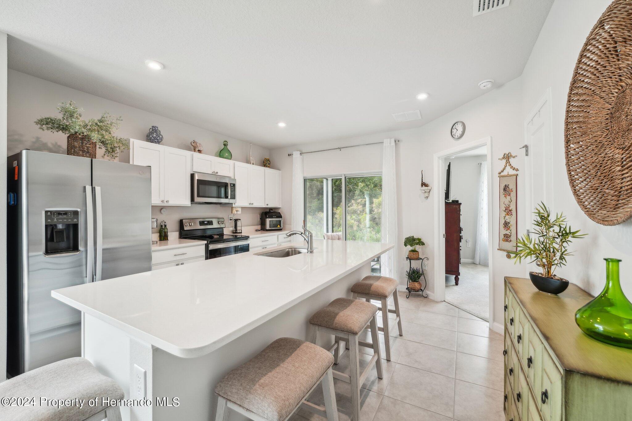 12214 Grizzly Lane New Port Richey, FL 34654 - Photo 13 of 49 a kitchen with stainless steel appliances a white table chairs and a refrigerator