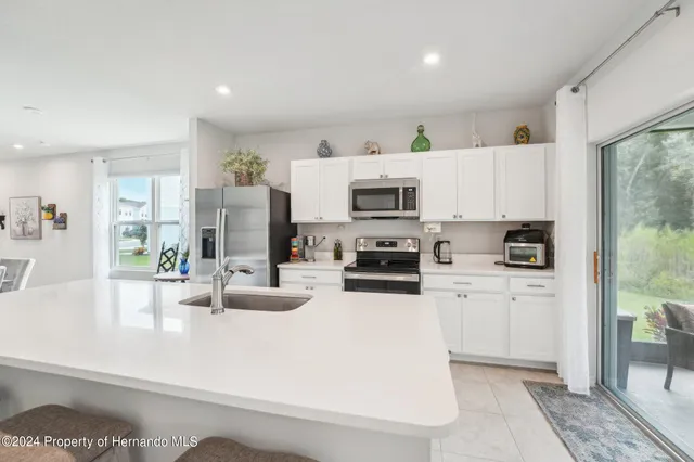 a kitchen with stainless steel appliances a stove a sink a microwave a refrigerator a counter top space and cabinets