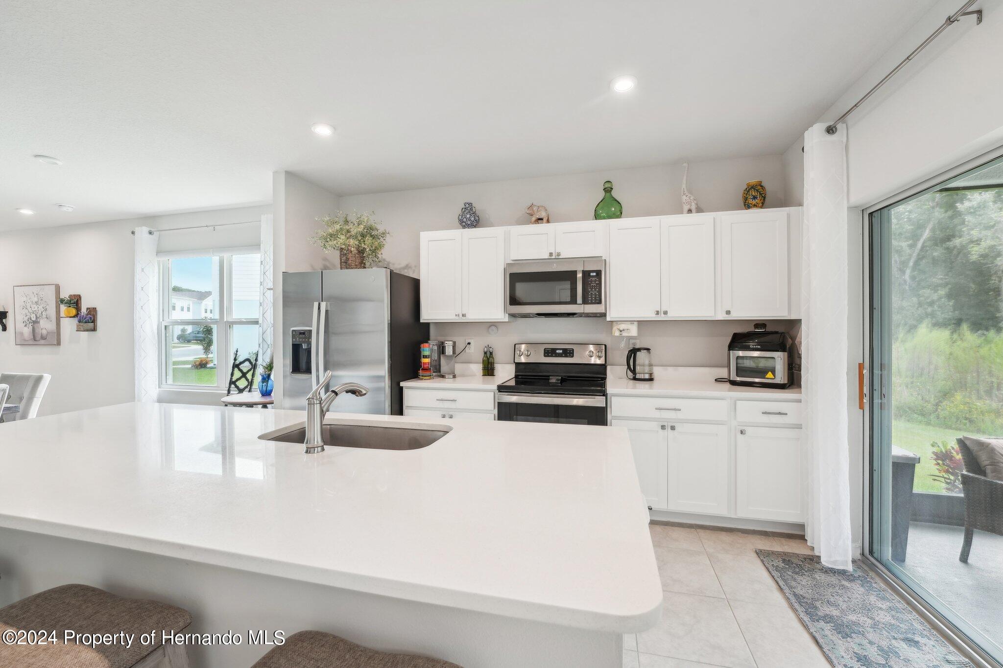 12214 Grizzly Lane New Port Richey, FL 34654 - Photo 18 of 49 a kitchen with stainless steel appliances a stove a sink a microwave a refrigerator a counter top space and cabinets