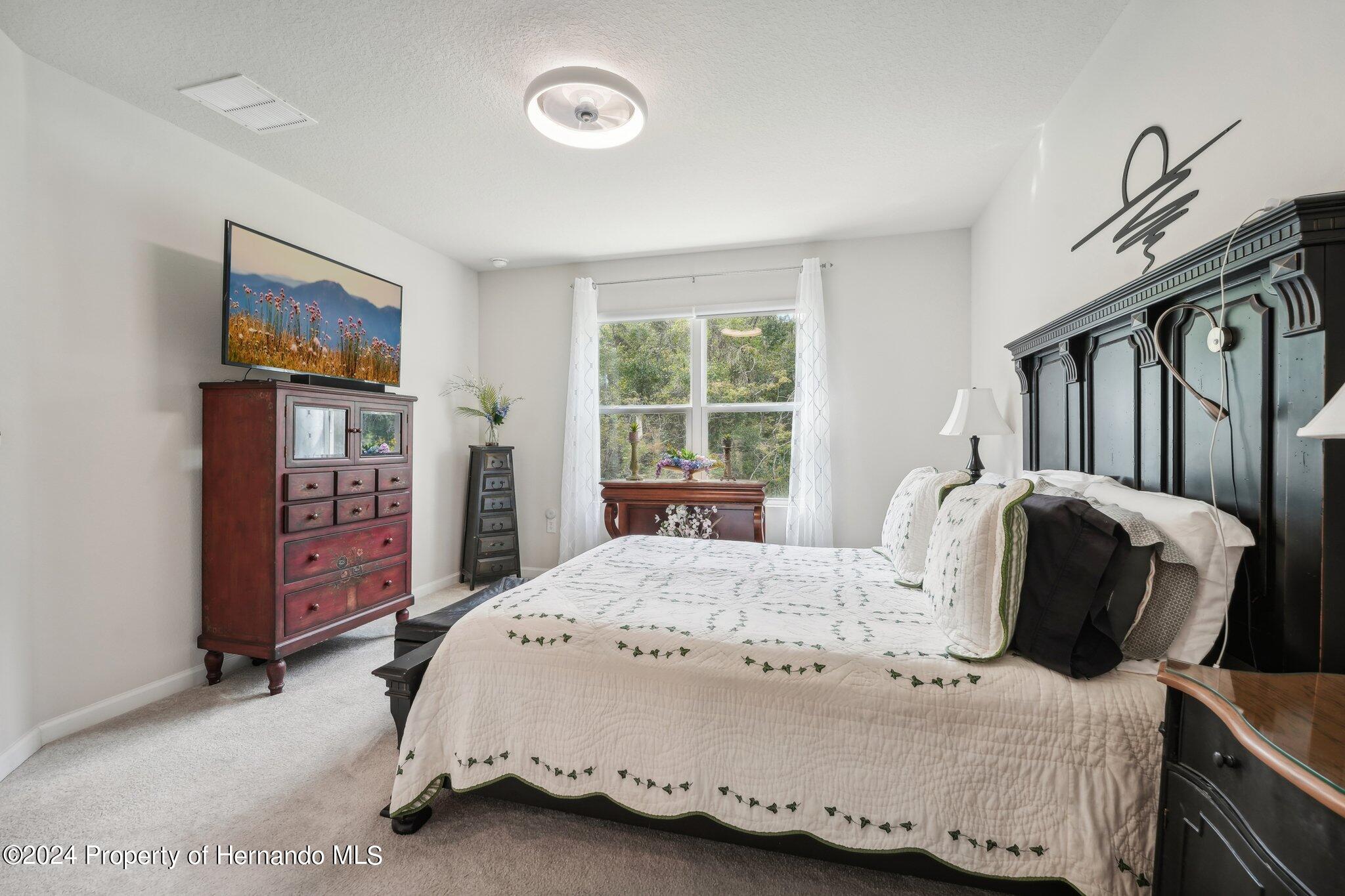 12214 Grizzly Lane New Port Richey, FL 34654 - Photo 28 of 49 a bedroom with a bed and dresser with wooden floor