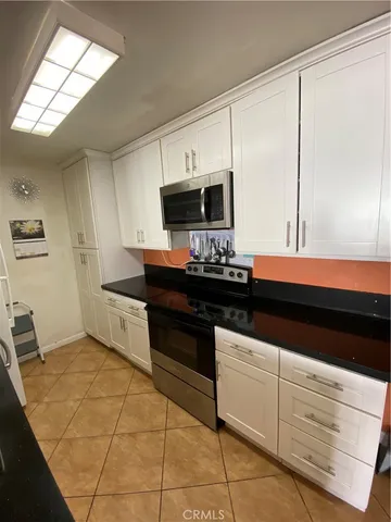 a kitchen with granite countertop white cabinets and black appliances