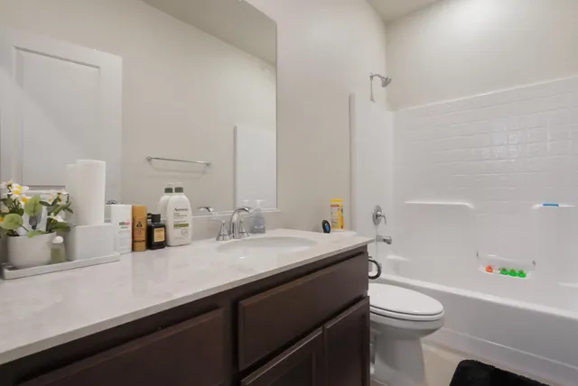 a bathroom with a granite countertop bathtub sink vanity mirror and toilet