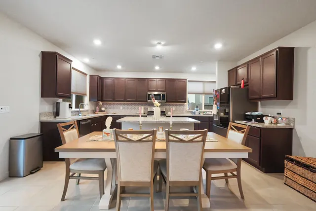 a kitchen with a dining table chairs refrigerator and microwave