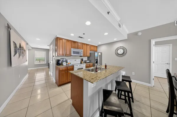 a kitchen with stainless steel appliances kitchen island granite countertop a table chairs and a refrigerator