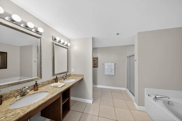 a spacious bathroom with a granite countertop double vanity sink a mirror and a shower