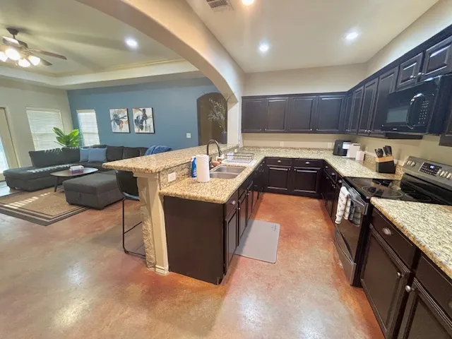 a kitchen with stainless steel appliances granite countertop a sink a stove and a refrigerator