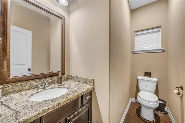 a bathroom with a granite countertop sink toilet and mirror