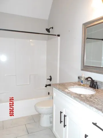 a bathroom with a granite countertop sink mirror vanity and toilet