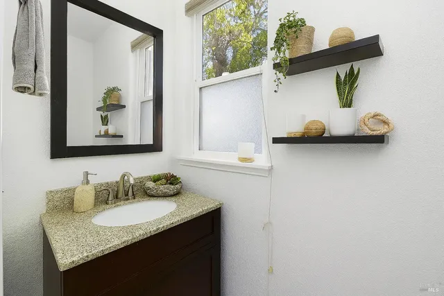 a bathroom with a granite countertop sink and a mirror