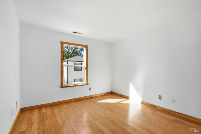 an empty room with wooden floor and a window