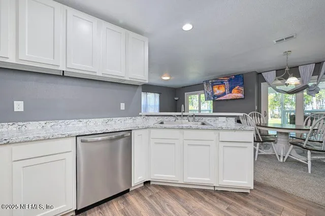 a kitchen with kitchen island granite countertop a sink cabinets and wooden floor