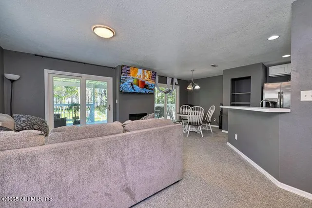 a living room with furniture a flat screen tv and a large window