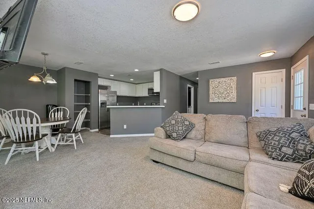 a living room with furniture and a refrigerator