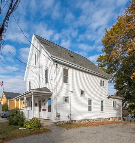 a view of a white house with large windows and a table and chairs