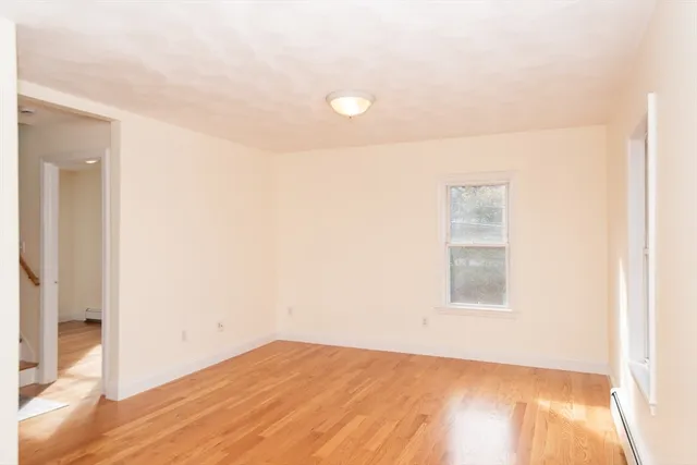 a view of an empty room with wooden floor and a window