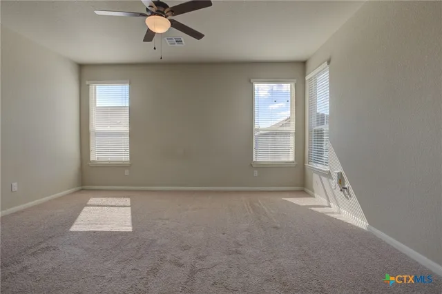 an empty room with windows and fan