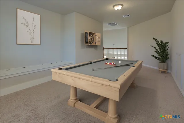 a living room with furniture pool table and potted plant