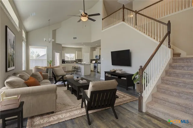 a living room with furniture flat screen tv and a ceiling fan