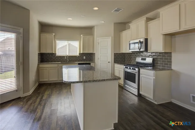 a kitchen with stainless steel appliances granite countertop wooden cabinets and a stove top oven