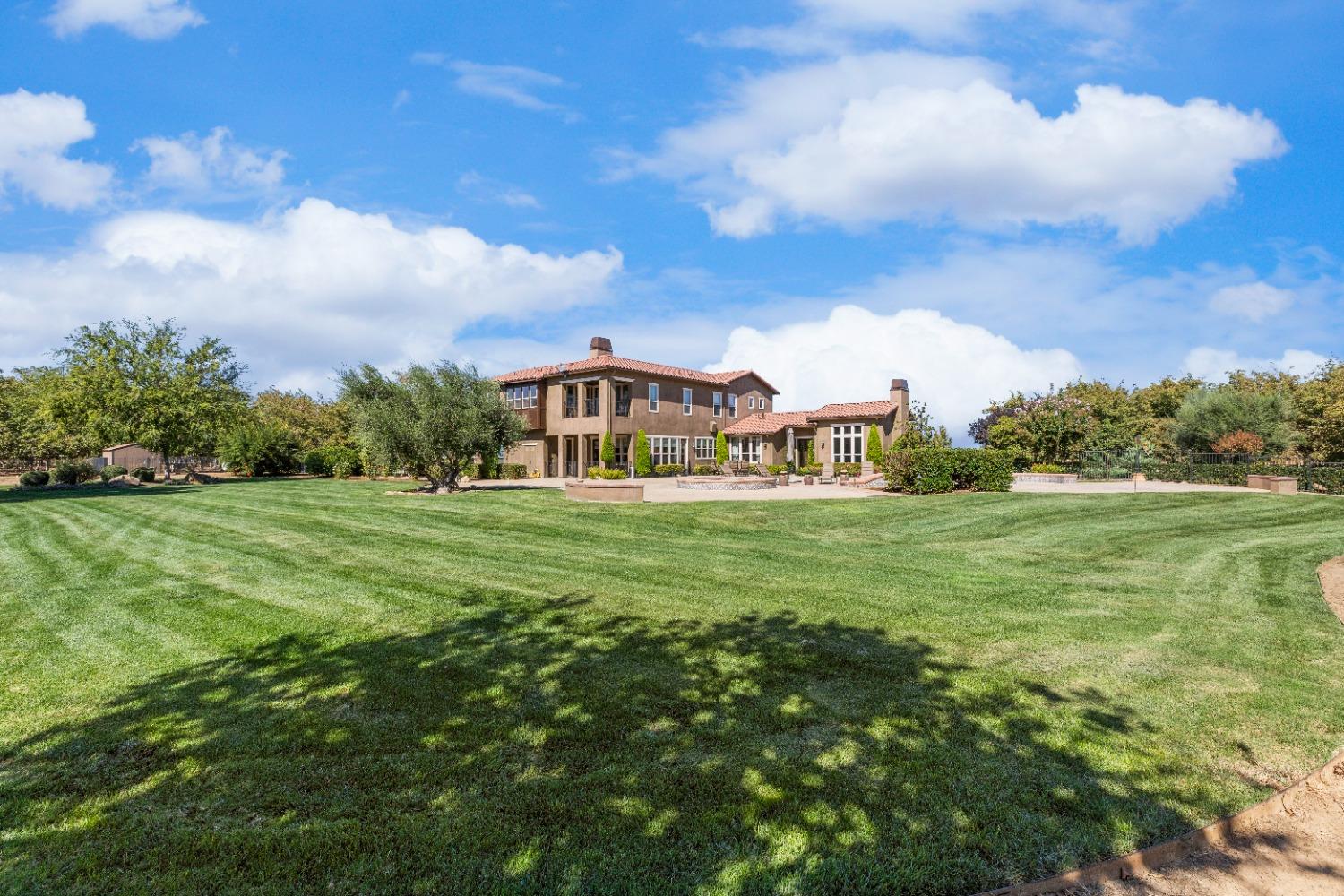 618 Elfers Road Patterson, CA 95363 - Photo 16 of 79 a view of a white house in front of a big yard with plants and large trees