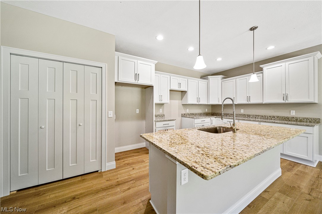 1745 Green Road Madison, OH 44057 - Photo 14 of 35 Kitchen featuring light hardwood / wood-style floors, decorative light fixtures, white cabinetry, and an island with sink