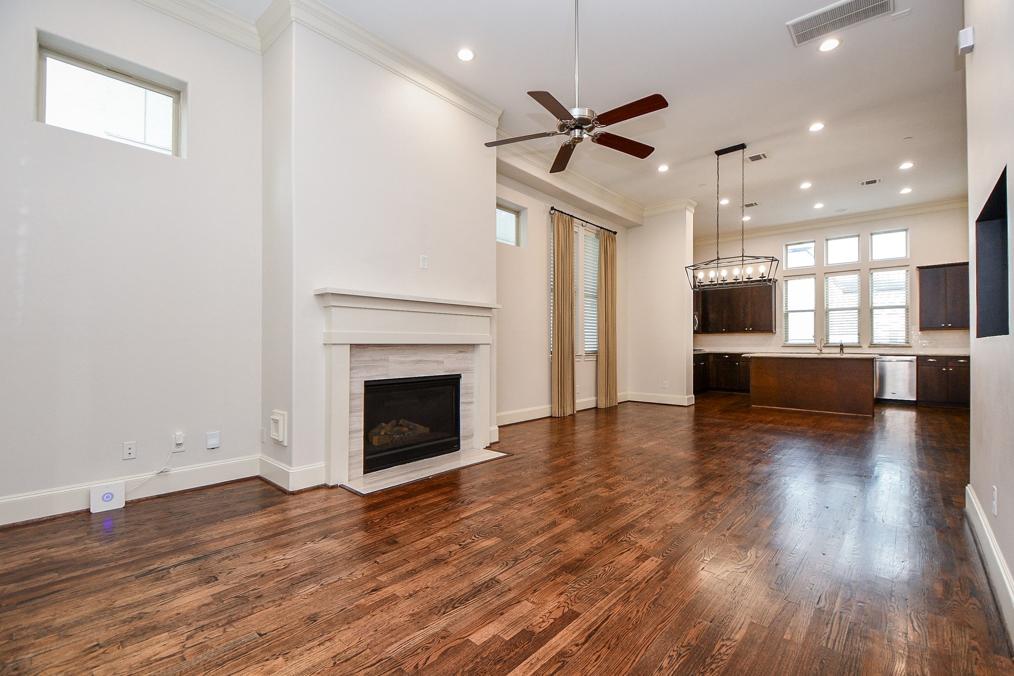 709 Delano Street Houston, TX 77003 - Photo 7 of 36 an empty room with wooden floor a fireplace and a kitchen