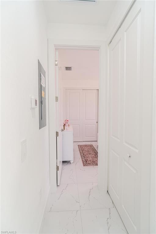 907 Homestead Road South Lehigh Acres, FL 33974 - Photo 24 of 43 Hallway featuring white walls, white tile flooring with gray veining, and a closet with bifold doors