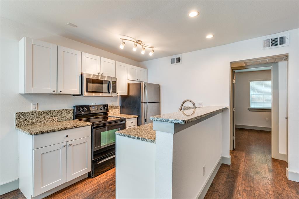 4633 Fairmount Street, Unit 109 Dallas, TX 75219 - Photo 8 of 14 Kitchen featuring granite countertops, white cabinetry, stainless steel appliances, wood-finish flooring, and recessed lighting
