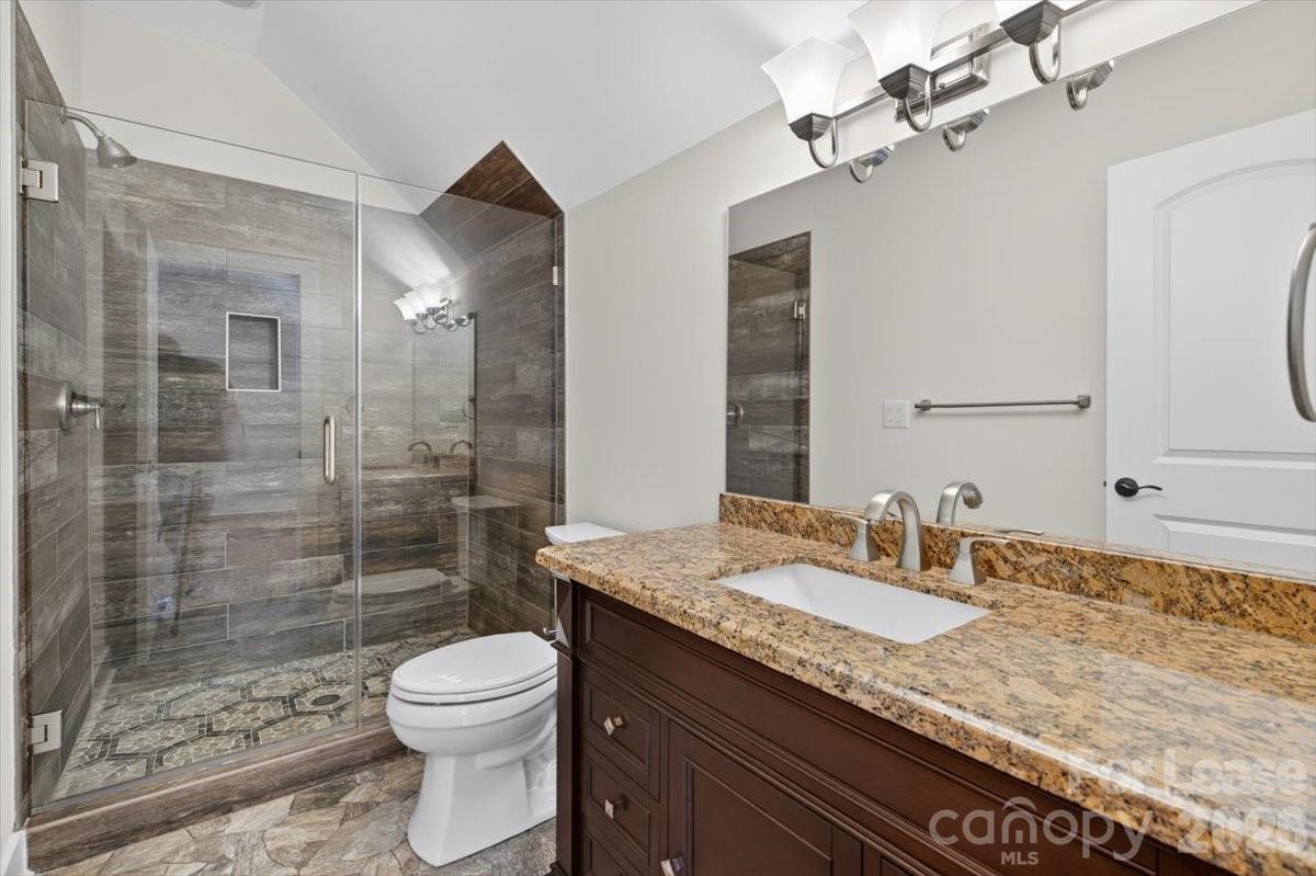 5201 Valley Stream Road Charlotte, NC 28209 - Photo 5 of 47 a bathroom with a granite countertop sink a toilet a mirror and shower