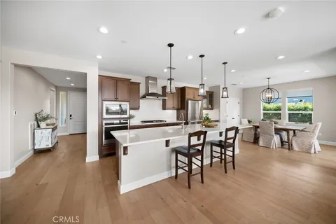 a kitchen with stainless steel appliances a dining table chairs stove a refrigerator and cabinets
