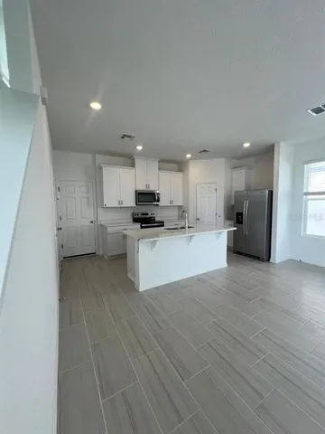a view of kitchen with a sink refrigerator and cabinets