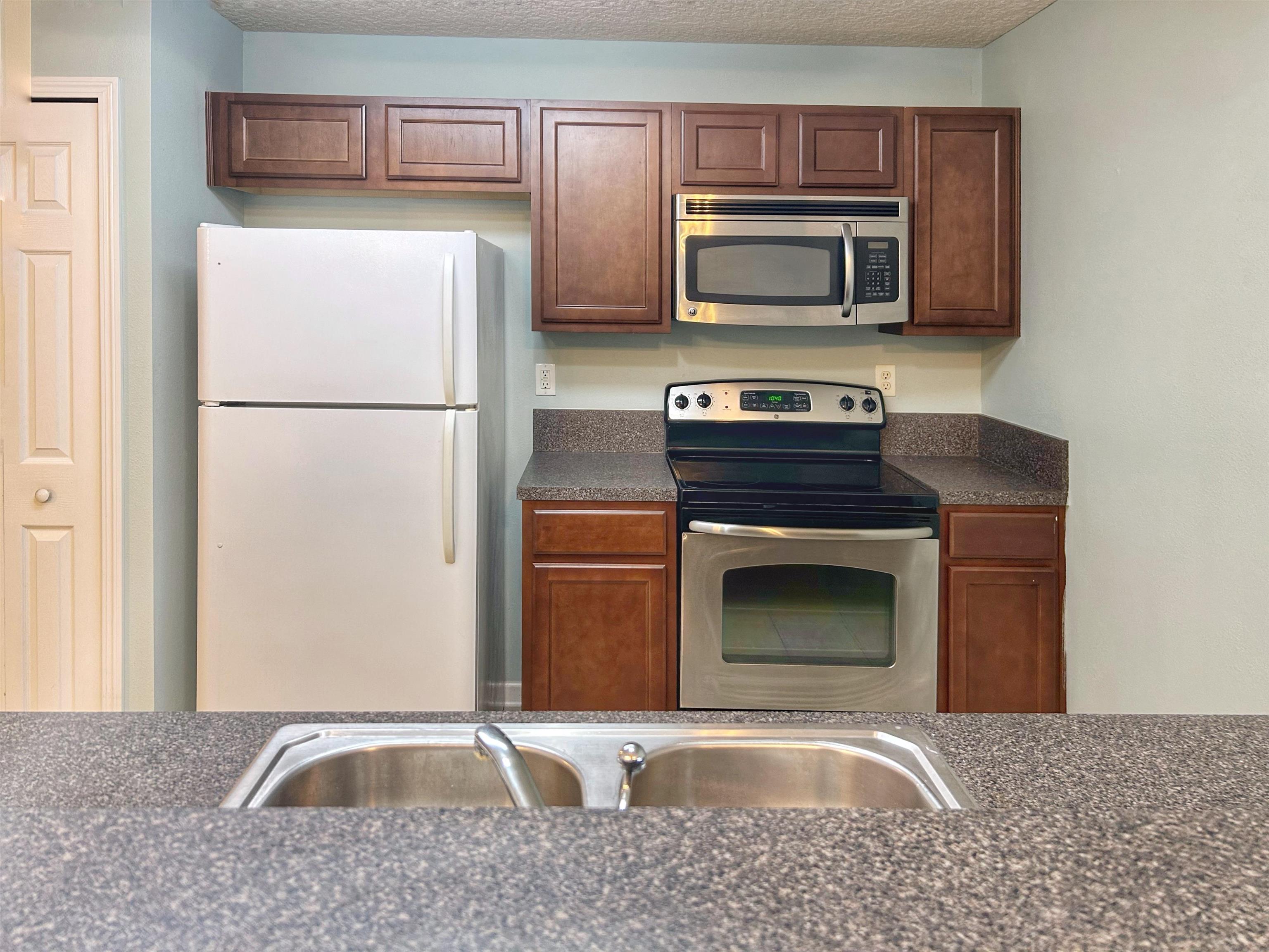 240 Golden Lake Loop St. Augustine, FL 32084 - Photo 5 of 28 a kitchen with granite countertop a refrigerator stove and microwave