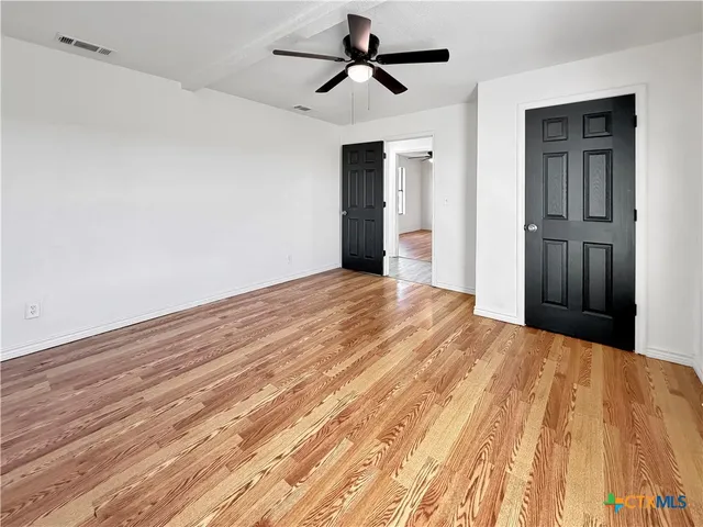 a view of a room with wooden floor and ceiling fan