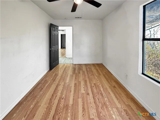 an empty room with windows and ceiling fan