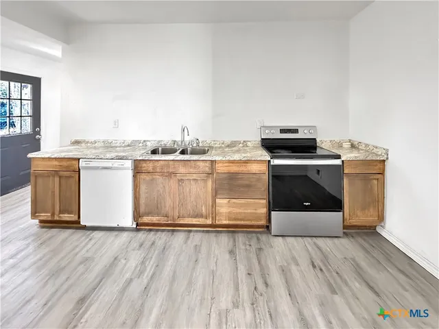 a kitchen with stainless steel appliances wooden floor and a stove top oven