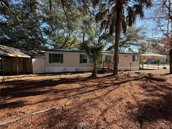 a view of a blue house with yard and a large tree