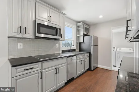 a kitchen with stainless steel appliances granite countertop white cabinets a microwave a sink and a refrigerator