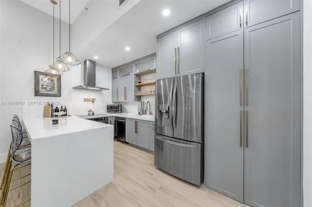 a kitchen with kitchen island a refrigerator a sink and a stove top oven