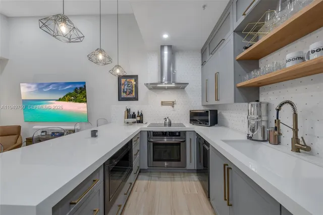 a kitchen with stainless steel appliances a sink dishwasher a stove top oven a refrigerator with island and cabinets