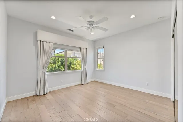 a view of an empty room with wooden floor and a ceiling fan