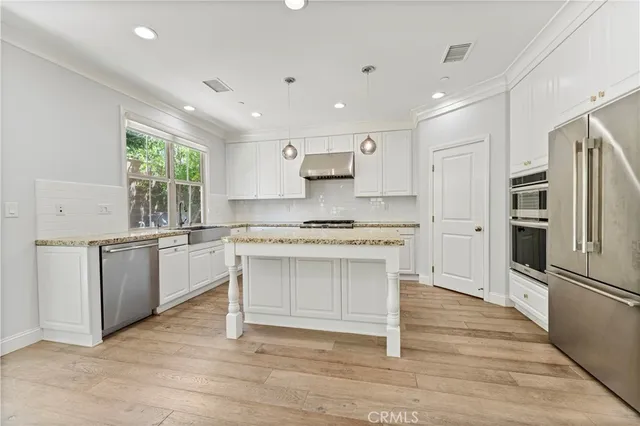 a kitchen with granite countertop a sink stainless steel appliances white cabinets and a window