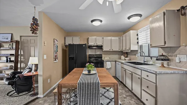 a kitchen with stainless steel appliances granite countertop a refrigerator a sink dishwasher a stove and a dining table with wooden floor