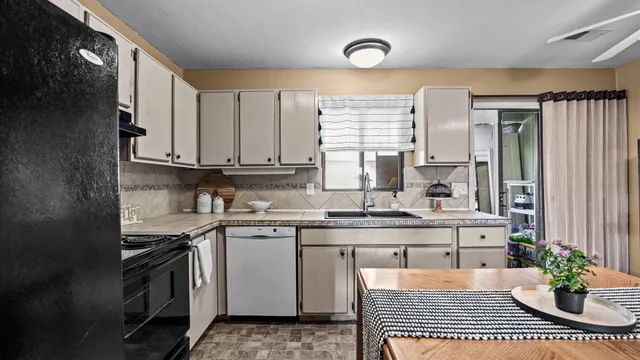 a kitchen with stainless steel appliances a sink a stove a refrigerator cabinets and a window