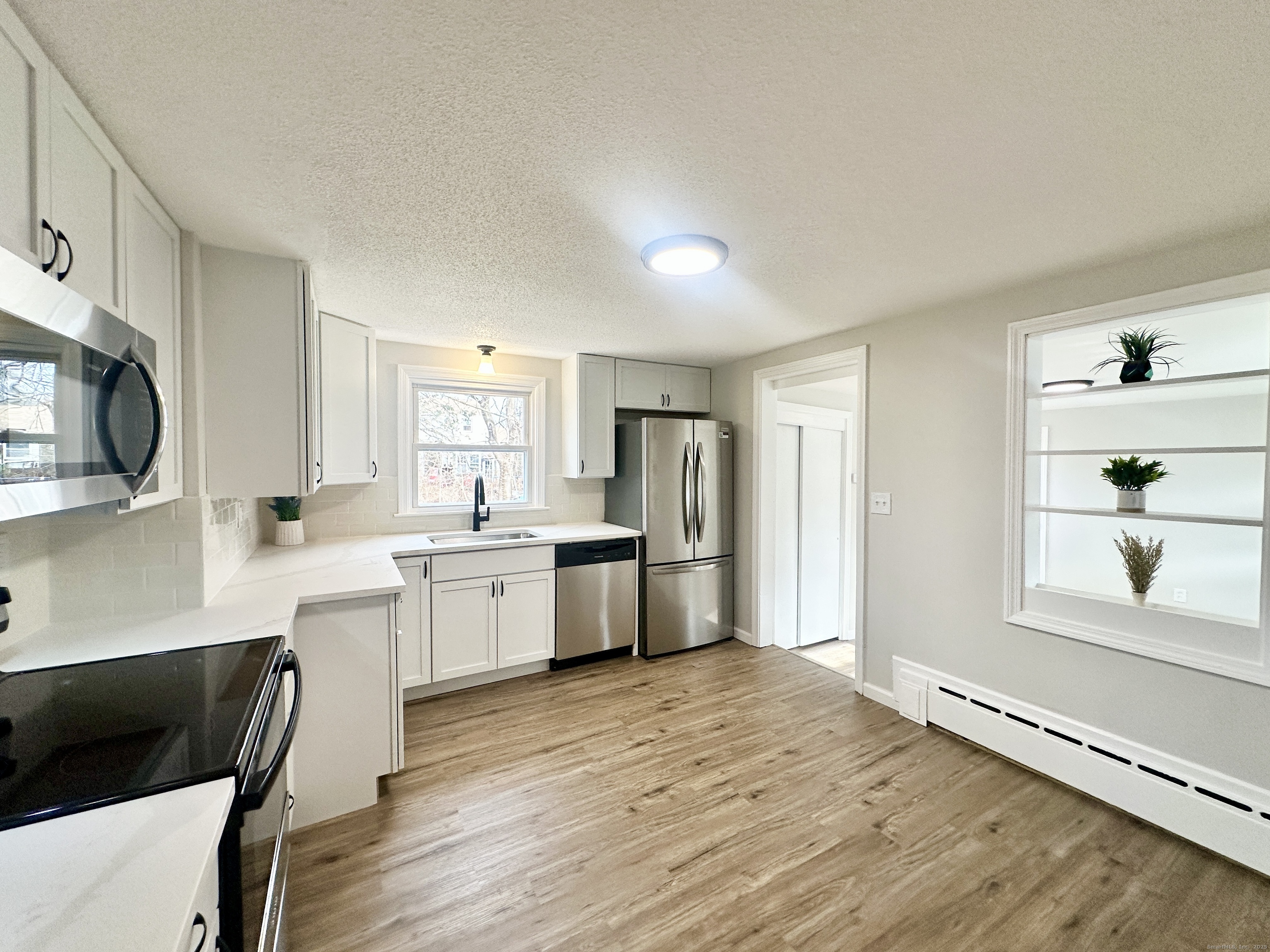9 Eleanor Road Enfield, CT 06082 - Photo 11 of 32 a large kitchen with cabinets wooden floor and stainless steel appliances